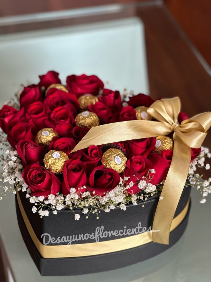 This may contain: a black box with red roses and chocolates in it on top of a table