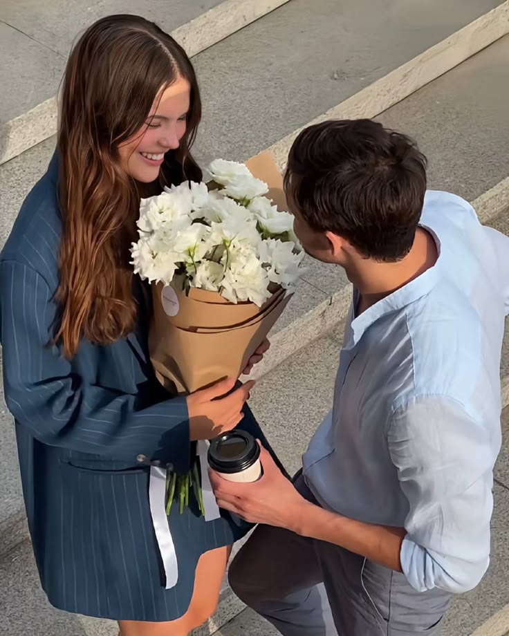 This may contain: a man holding a bouquet of white flowers next to a woman